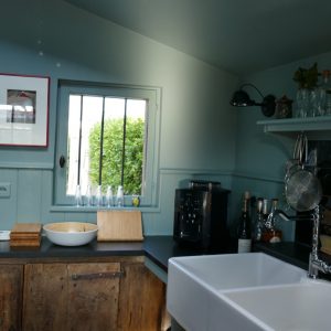 Küche in hellblau mit Waschbecken und Kaffemaschine und kleinem Fenster mit Blick auf den Hof