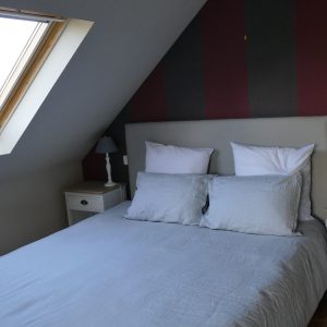 Gemütliches Schlafzimmer mit Doppelbett unter einer Schräge mit Veluxfenster