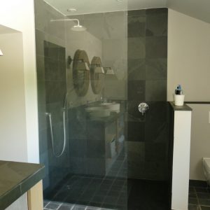 Geräumiges Badezimmer in creme und dunkelgrau mit Glasdusche und Nisch mit WC